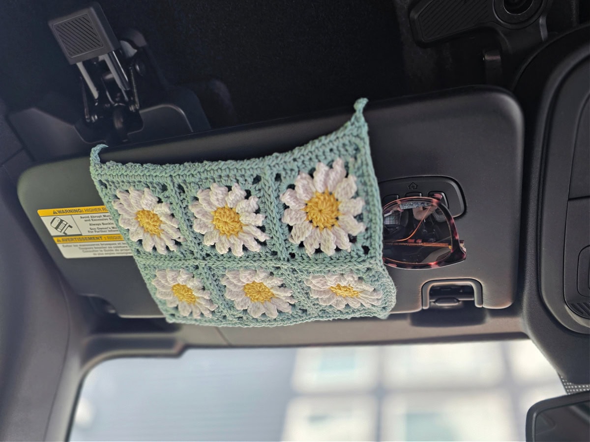 A crochet car visor sunglasses holder in a car made from six daisy granny squares.