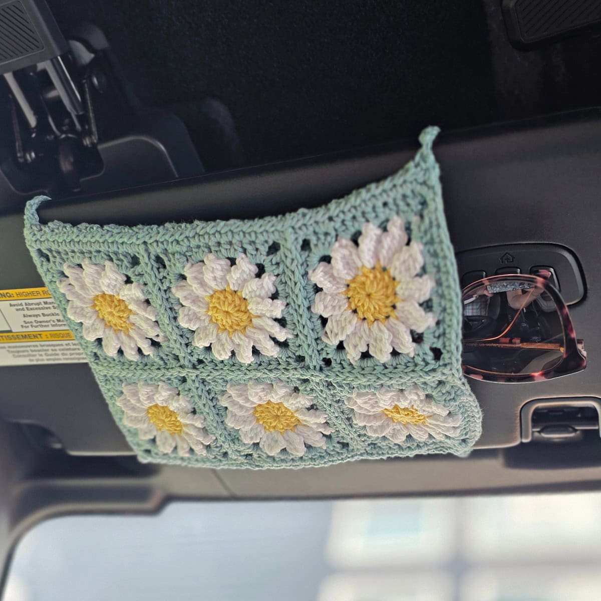 A crochet sunglasses car visor in a car made from six daisy granny squares.