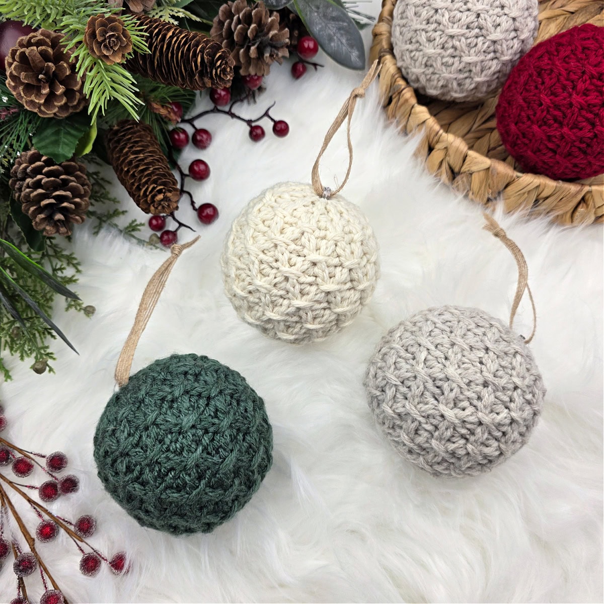 Crochet Christmas baubles in neutral and holiday colors laying on a bamboo tray and fur rug.