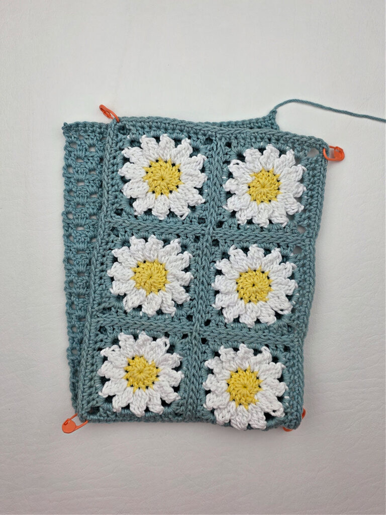 Six completed crochet daisy granny squares on a white surface.