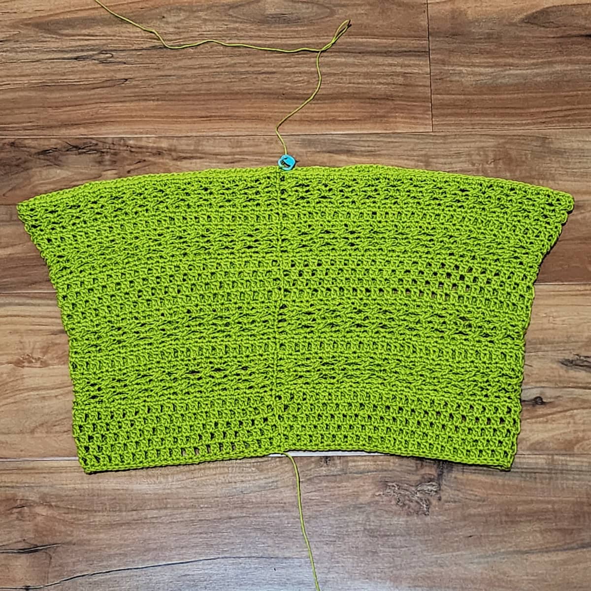 Green crochet panel against a wooden floor.