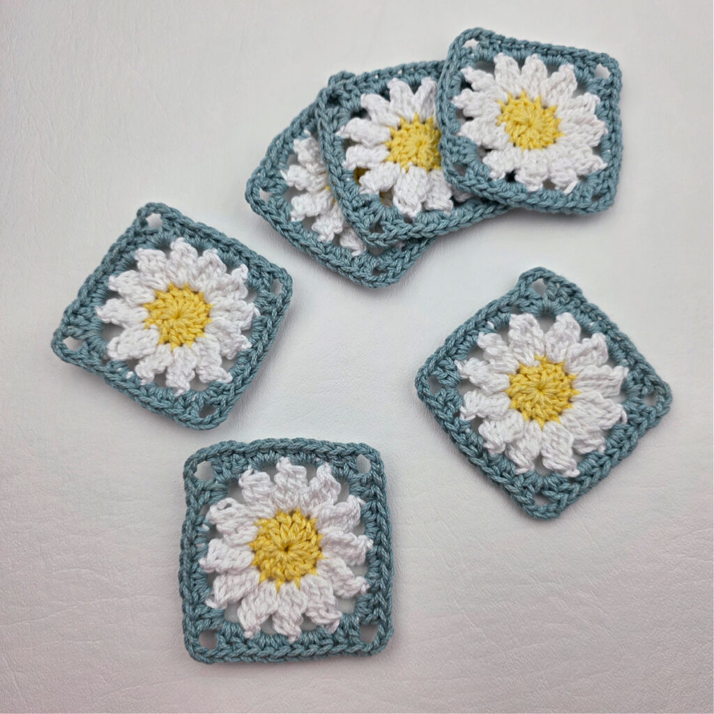 Six completed crochet daisy granny squares on a white surface.