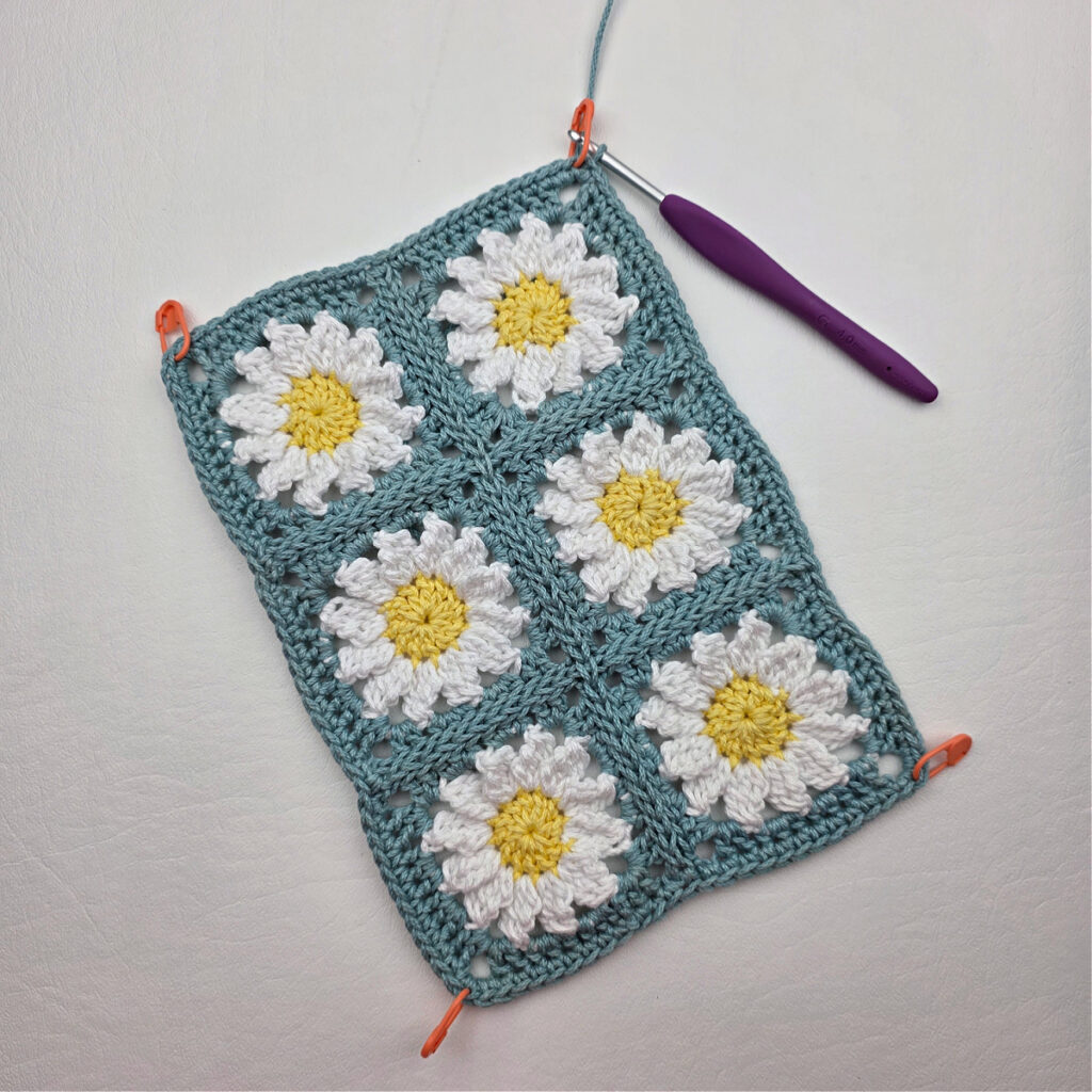 Six completed crochet daisy granny squares on a white surface.