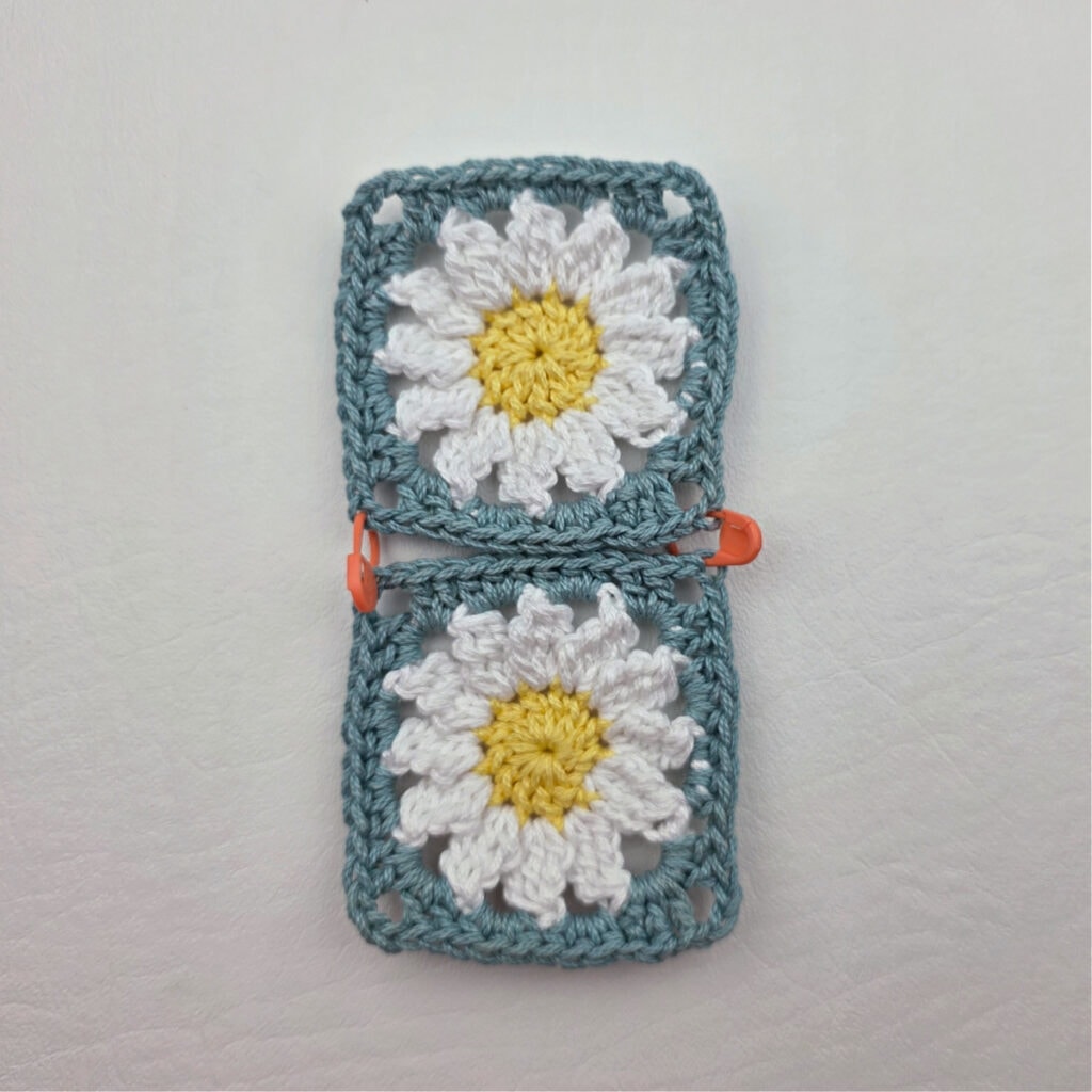 Two completed crochet daisy granny squares on a white surface.