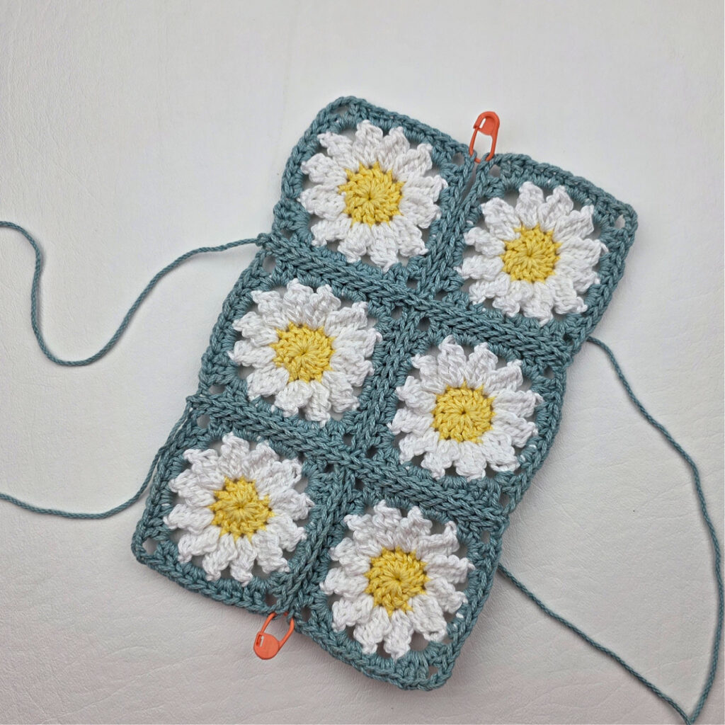 Six completed crochet daisy granny squares on a white surface.