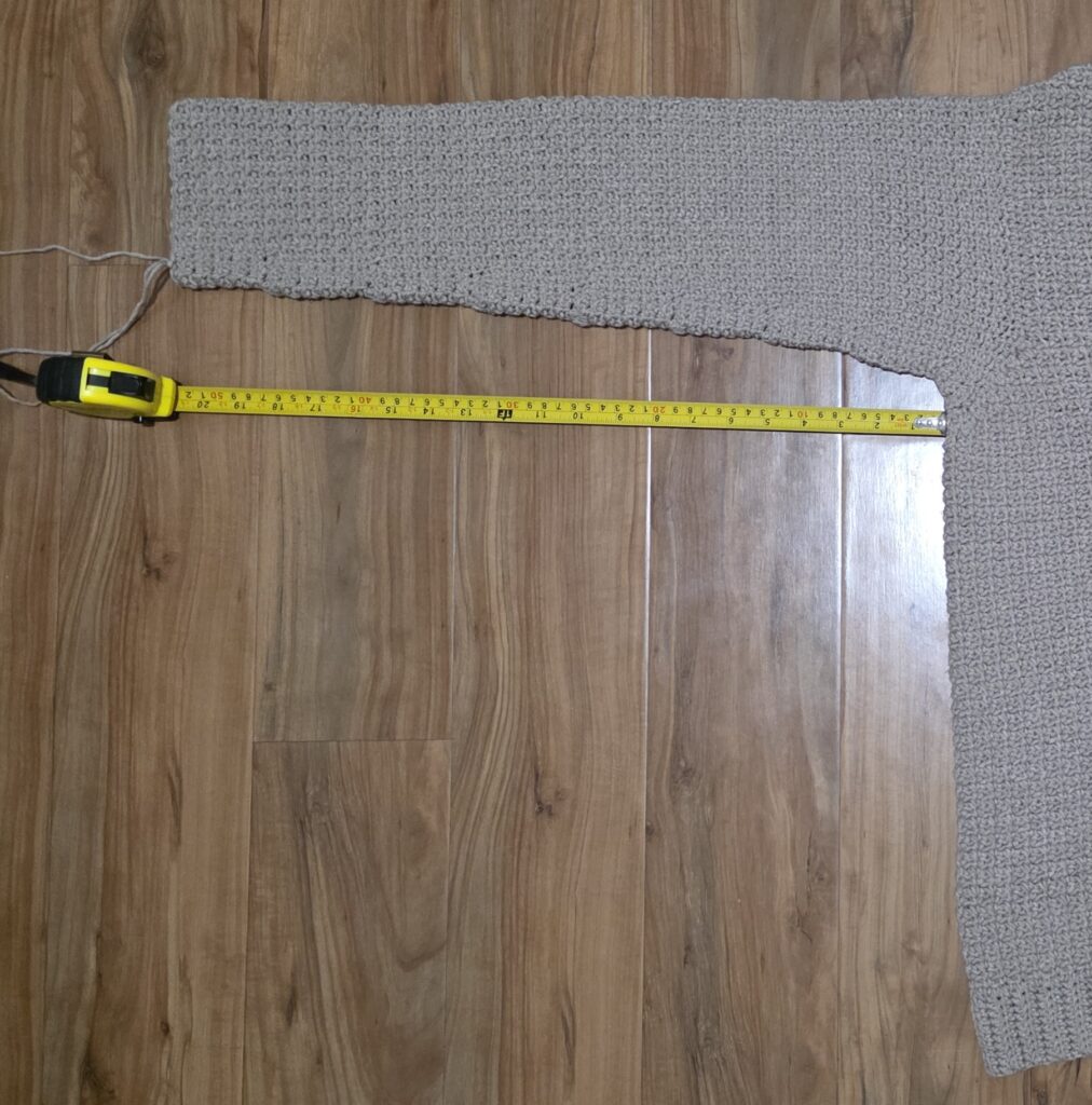 Measuring the completed sleeve of the crochet sweater.