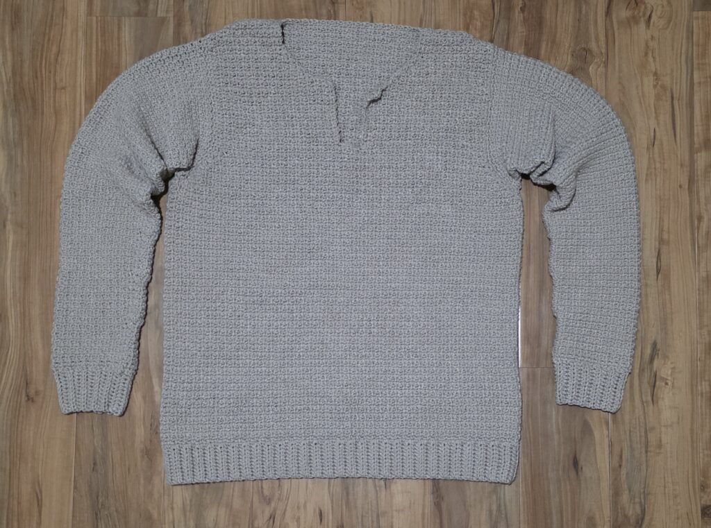 Crochet men's sweater against a wooden background.