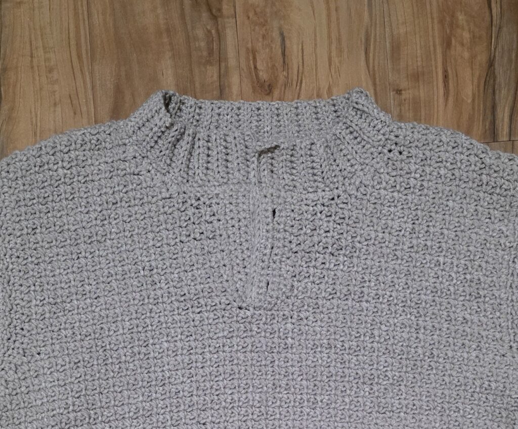 The collar of the crochet sweater against a wooden background.
