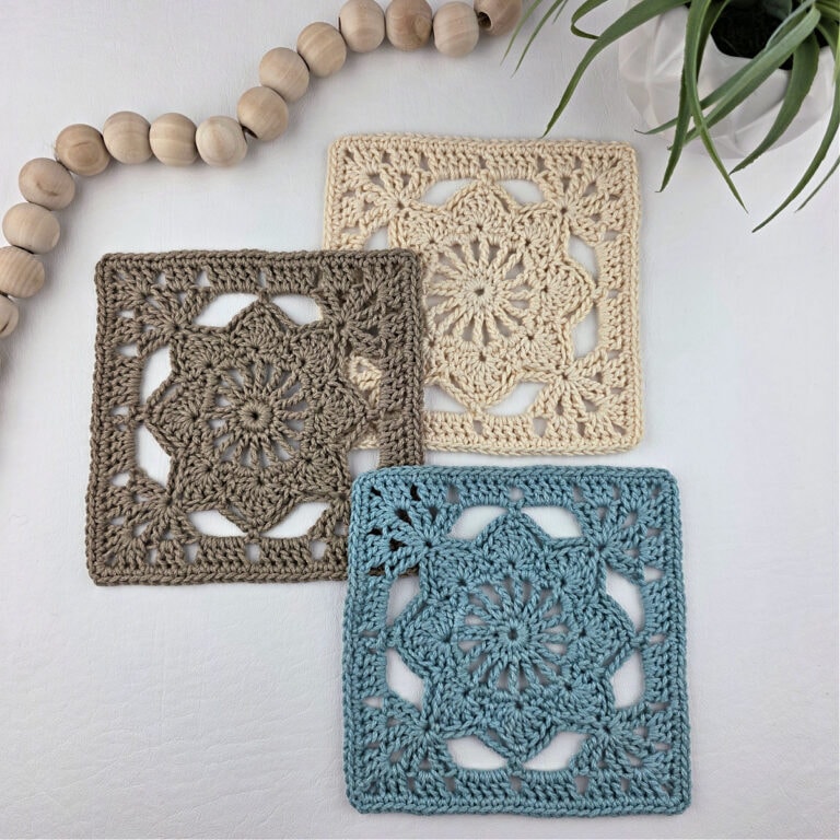 Blue, brown, and white colored granny square flower motifs laid out with white beads in the corner.