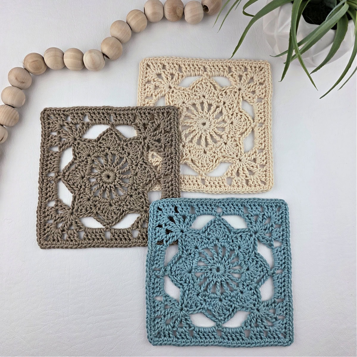 Blue, brown, and white colored granny square flower motifs laid out with white beads in the corner.