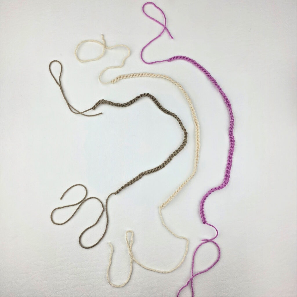 Three strands of yarn -- pink, white, and brown.