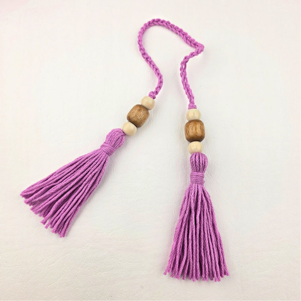 Two pink handmade yarn tassels with beads.