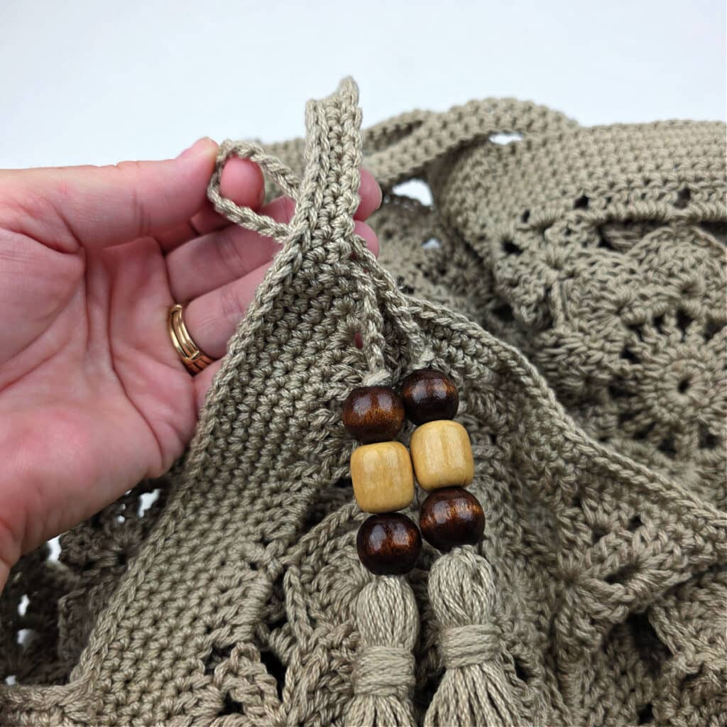 Tassels attached to the top of a crochet granny square bag.