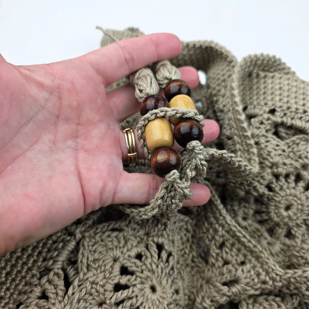 Tassels attached to the top of a crochet granny square bag.