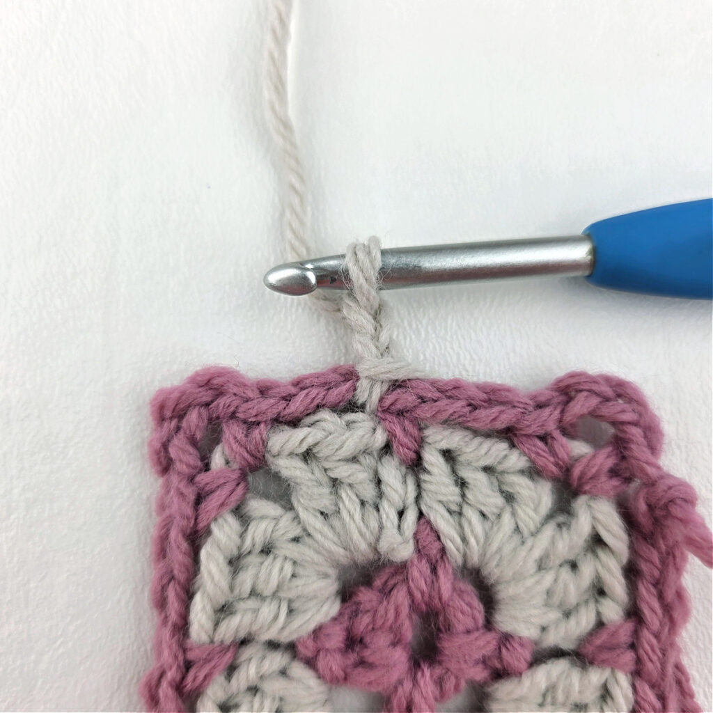 Making a block stitch granny square with a blue crochet hook.