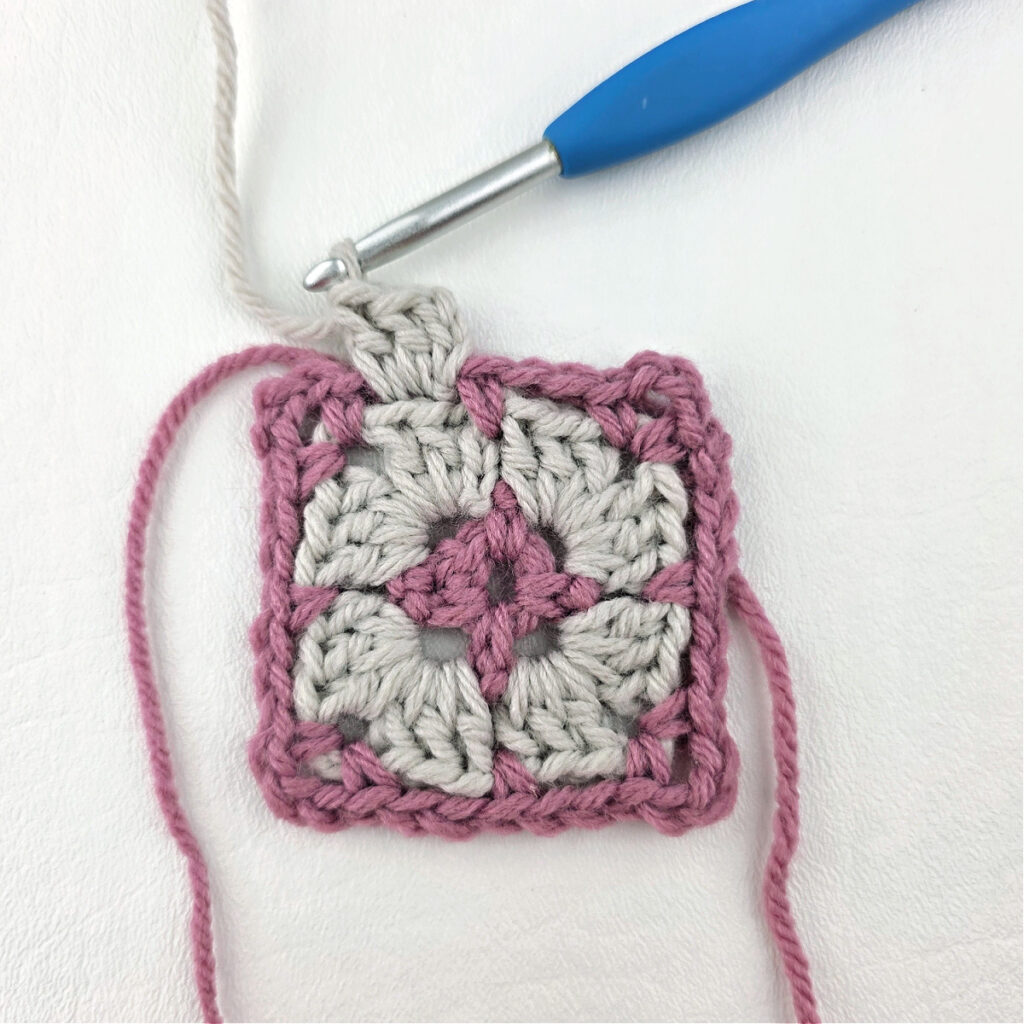 Making a block stitch granny square with a blue crochet hook.