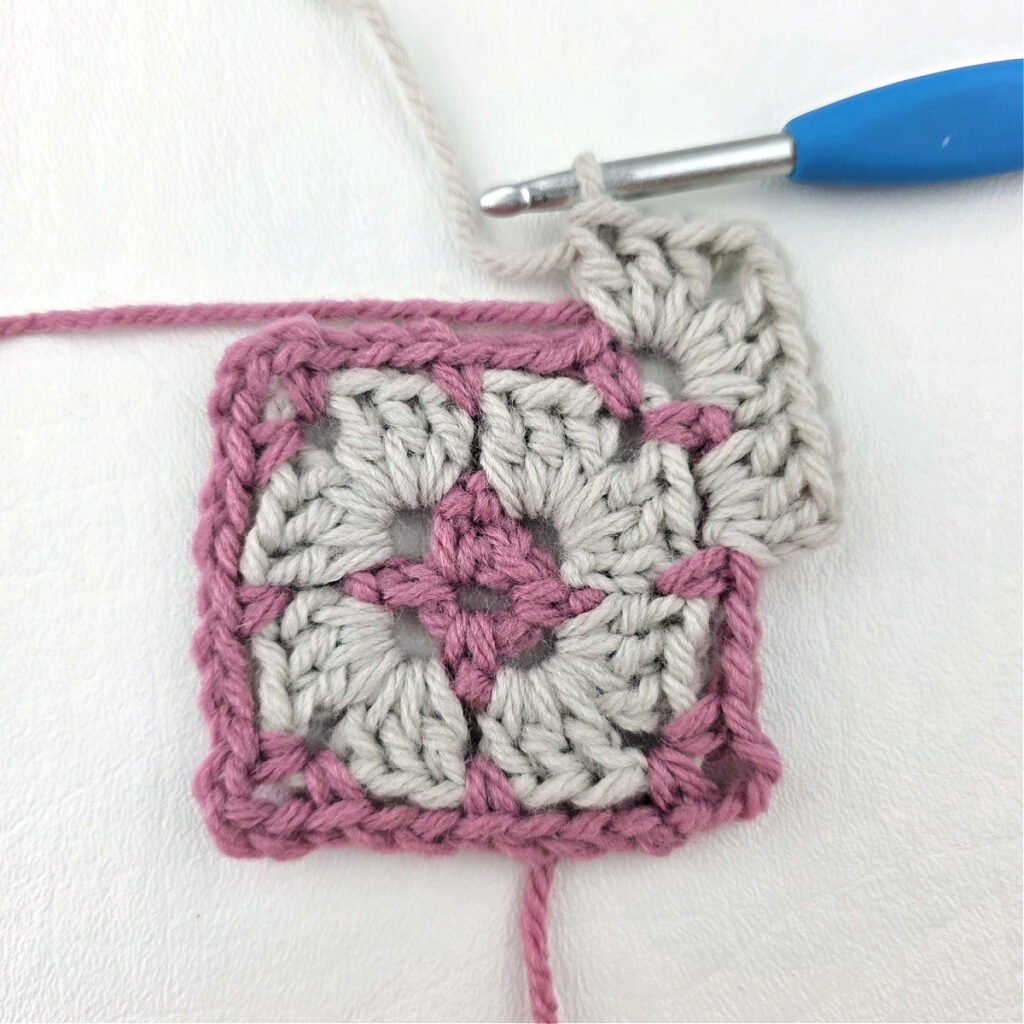 Making a block stitch granny square with a blue crochet hook.