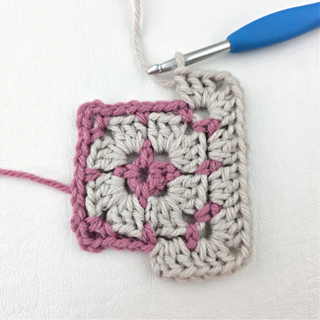 Making a block stitch granny square with a blue crochet hook.