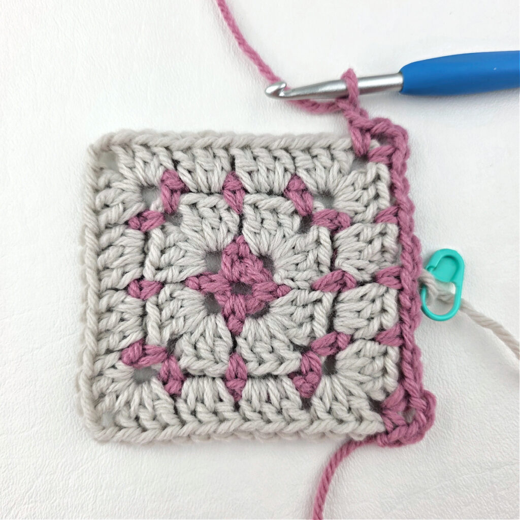 Making a block stitch granny square with a blue crochet hook.