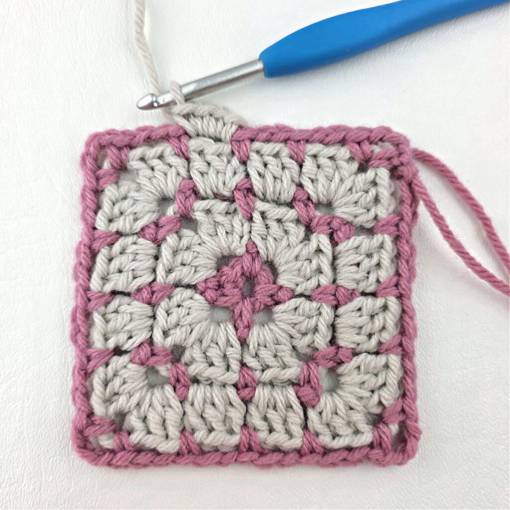 Making a block stitch granny square with a blue crochet hook.