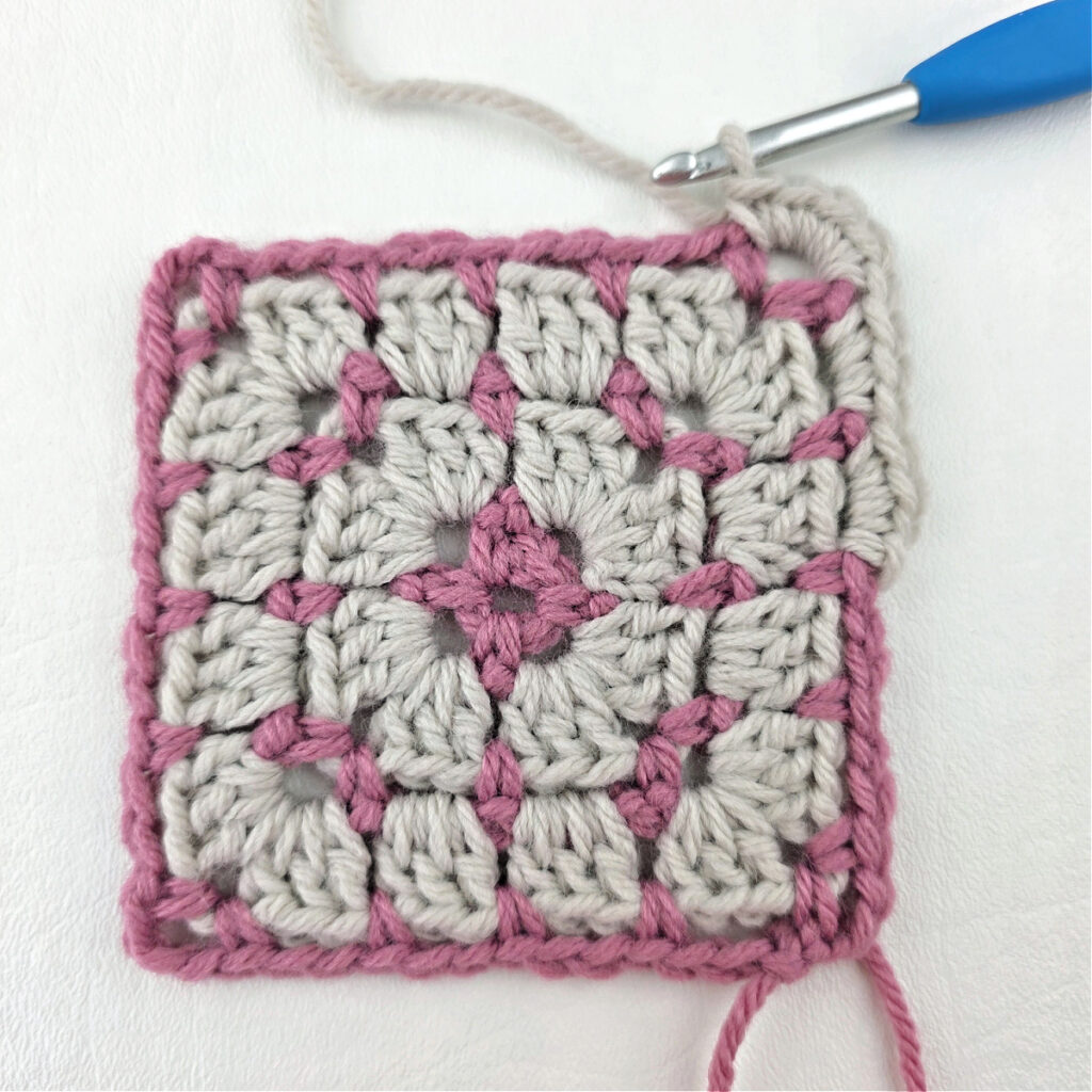 Making a block stitch granny square with a blue crochet hook.