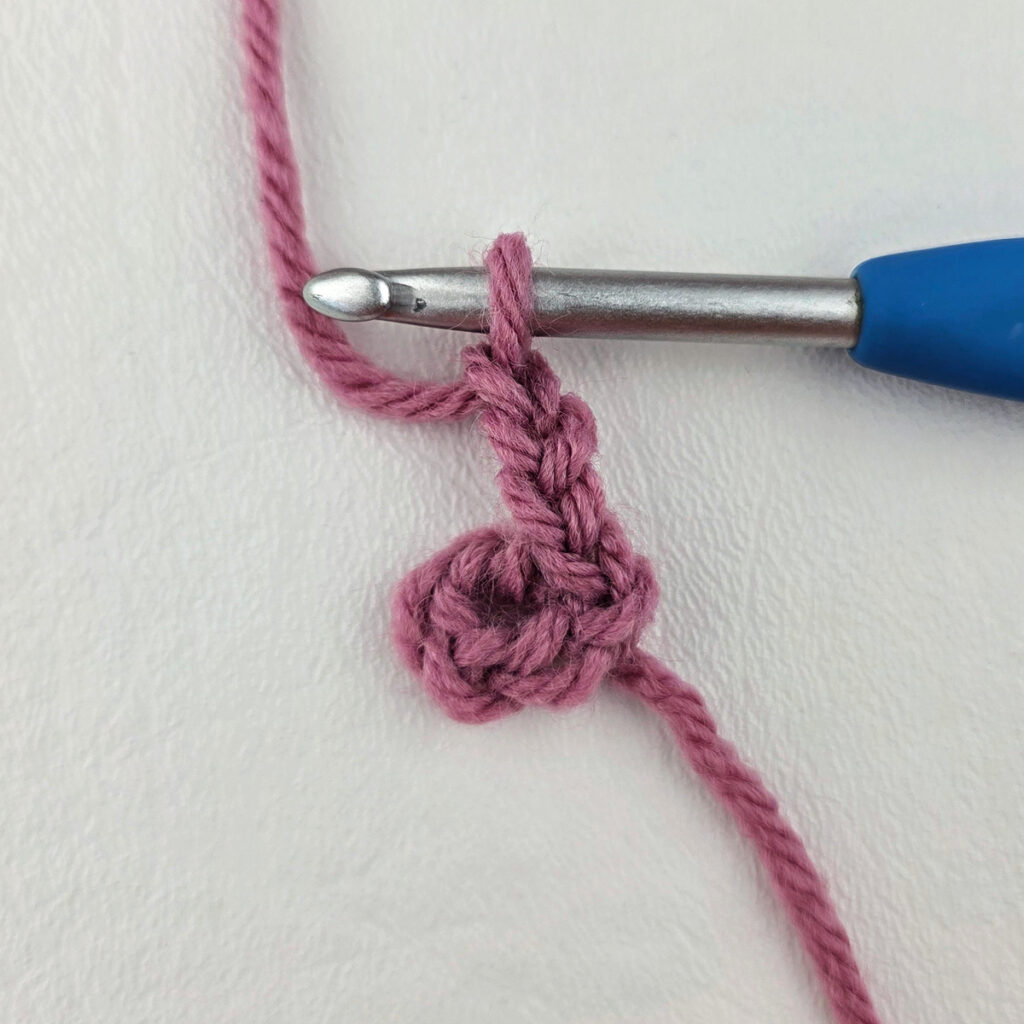 Making a block stitch granny square with a blue crochet hook.