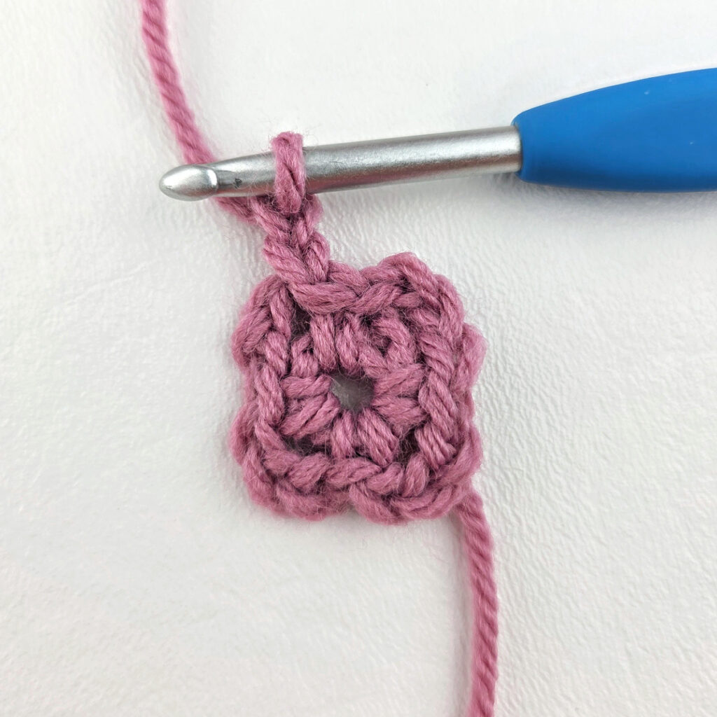 Making a block stitch granny square with a blue crochet hook.