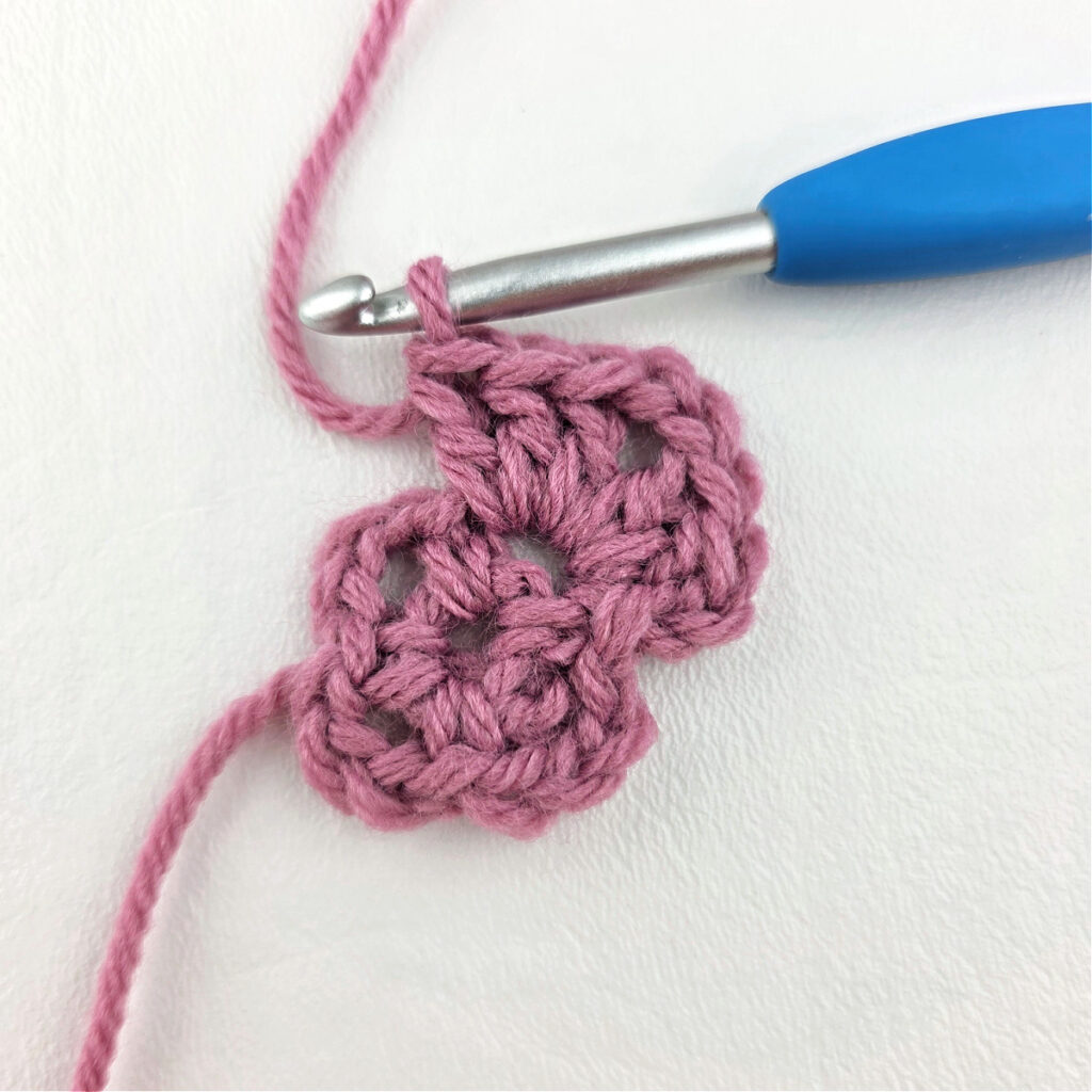 Making a block stitch granny square with a blue crochet hook.