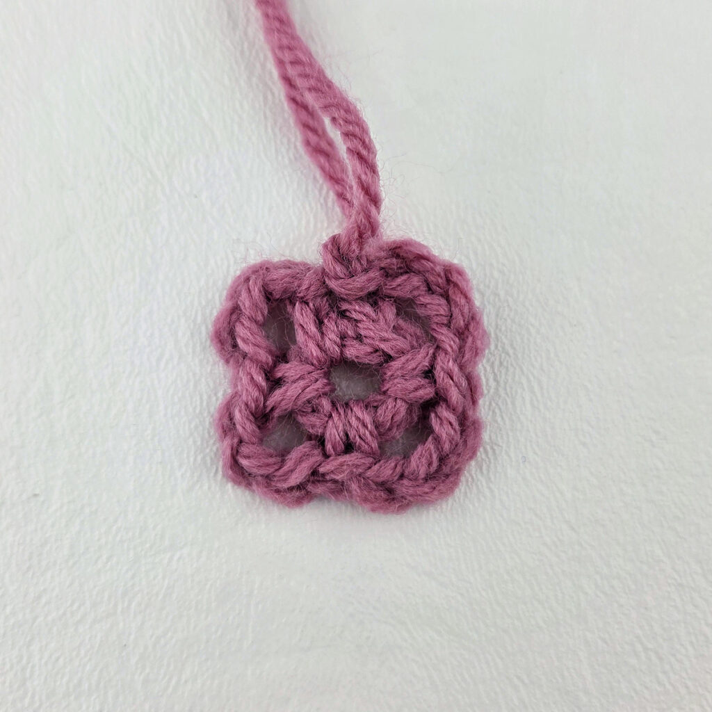Making a block stitch granny square with a blue crochet hook.