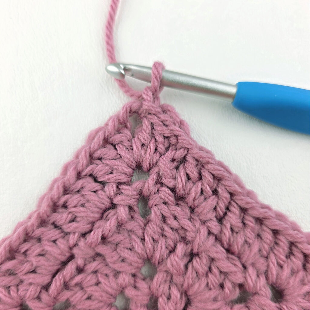 Making a block stitch granny square with a blue crochet hook.