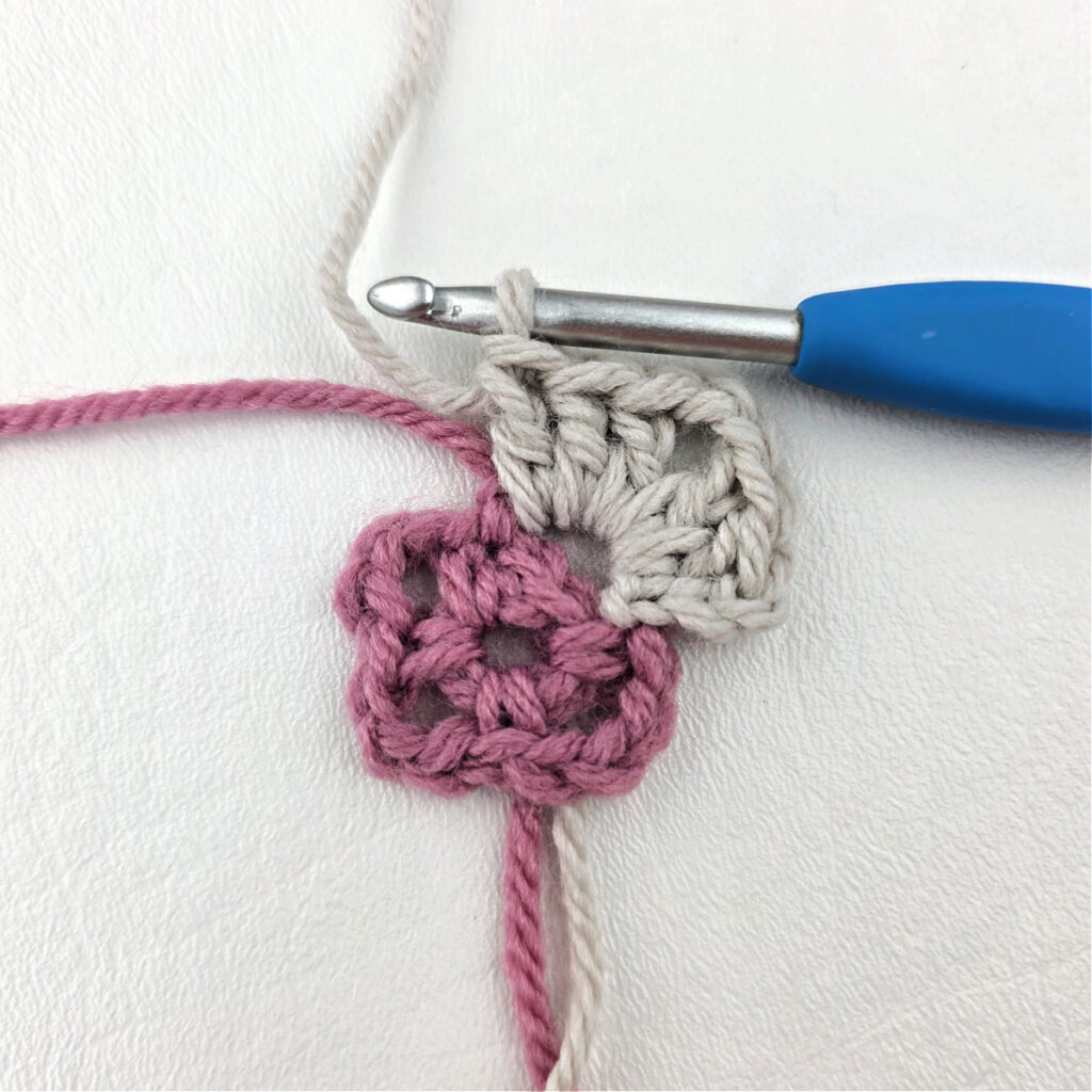Making a block stitch granny square with a blue crochet hook.