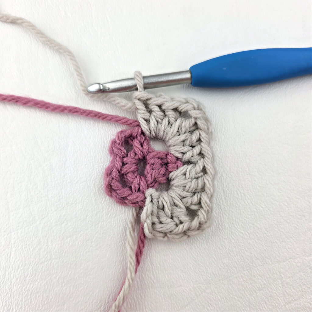 Making a block stitch granny square with a blue crochet hook.