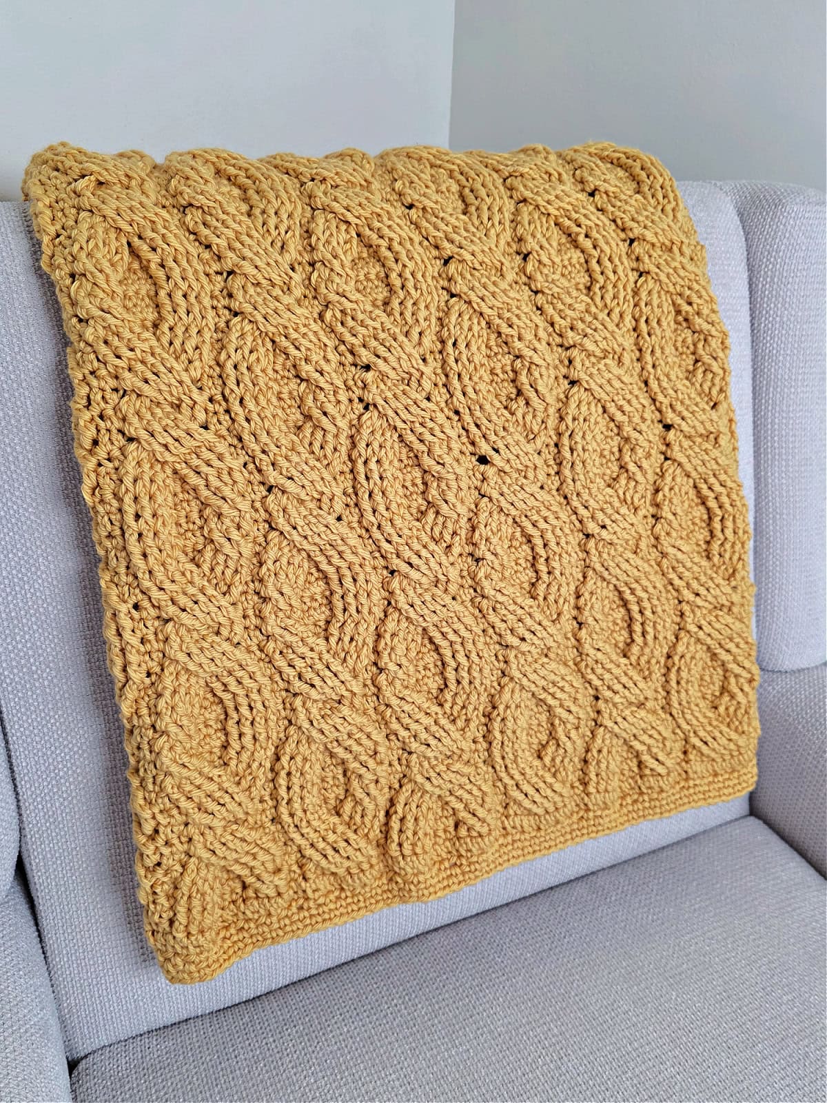 Yellow crochet blanket folded over a sofa chair.