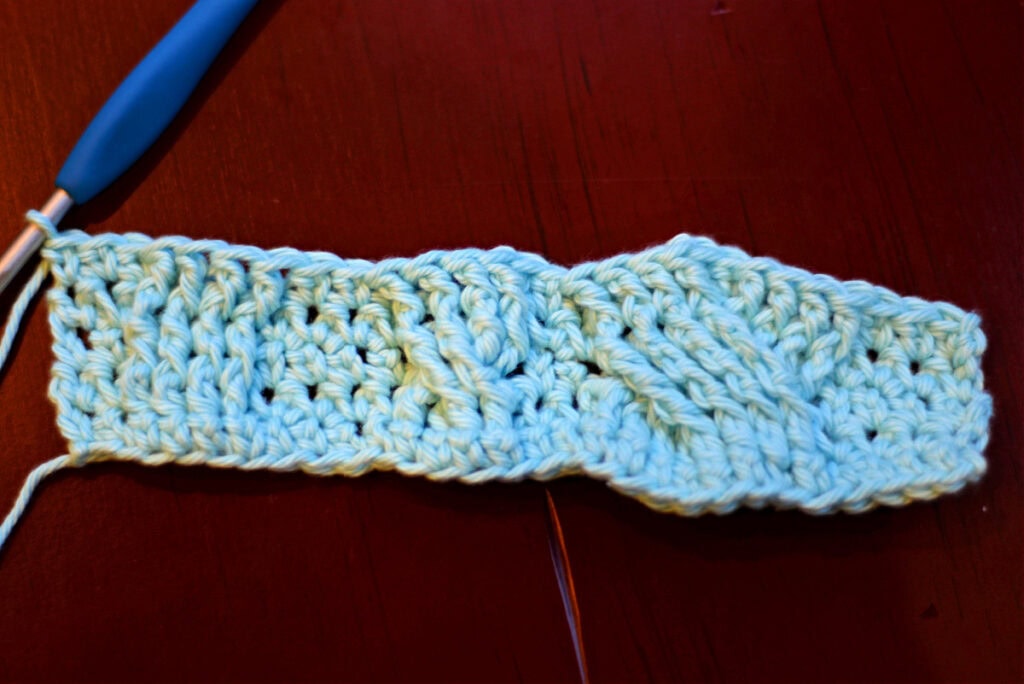 Creating crochet cables with a blue crochet hook.