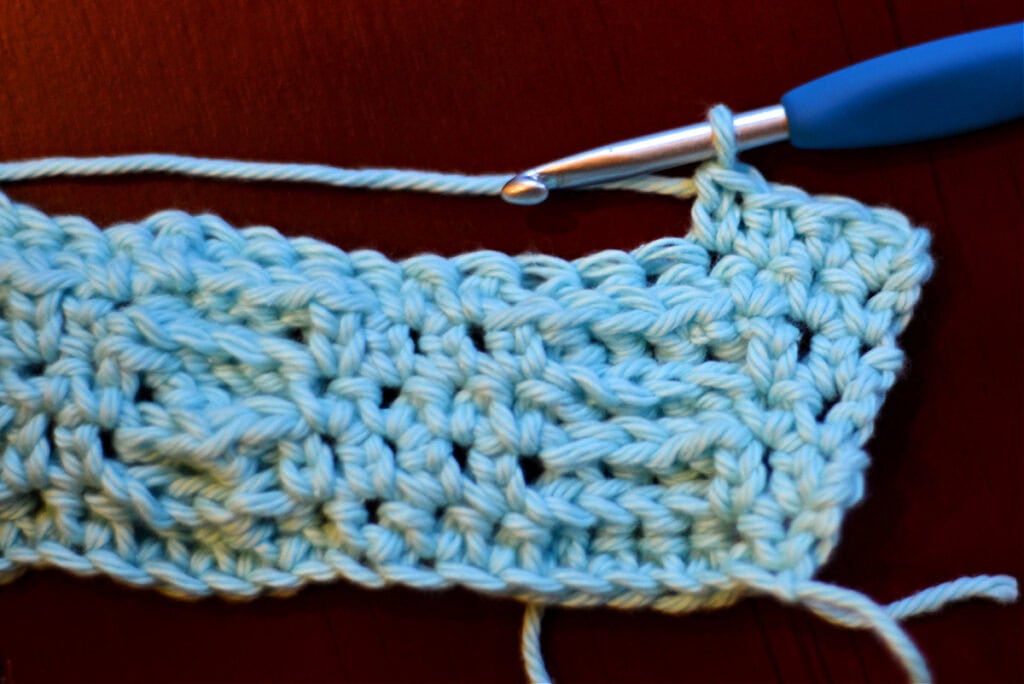 Creating crochet cables with a blue crochet hook.