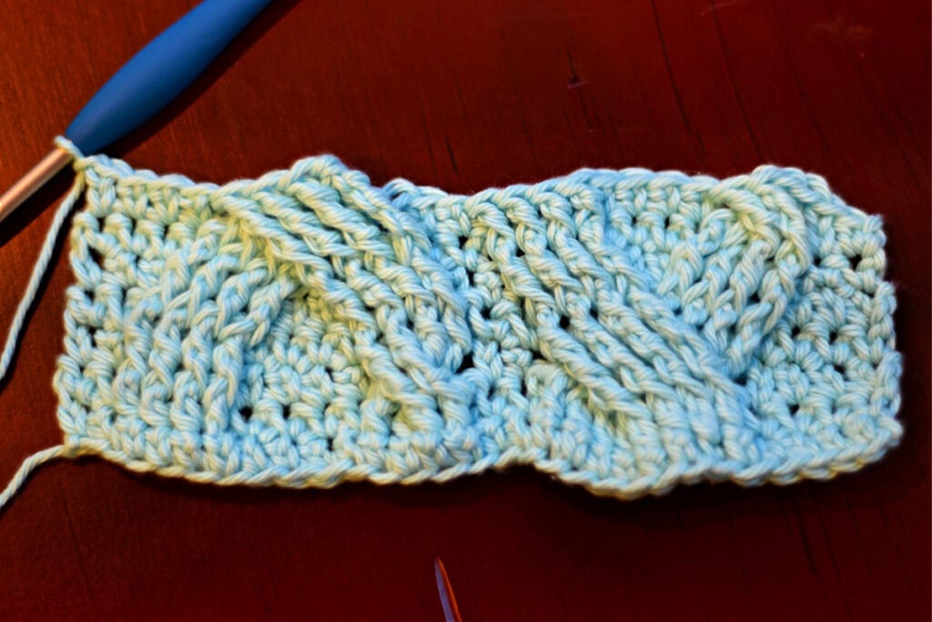 Creating crochet cables with a blue crochet hook.