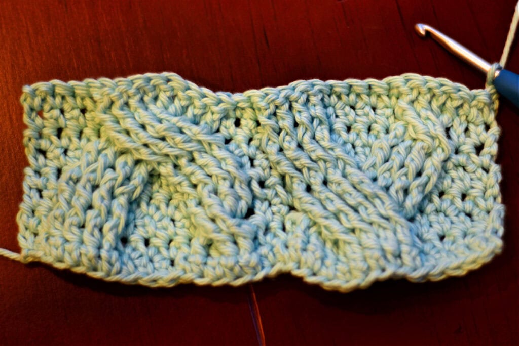 Creating crochet cables with a blue crochet hook.