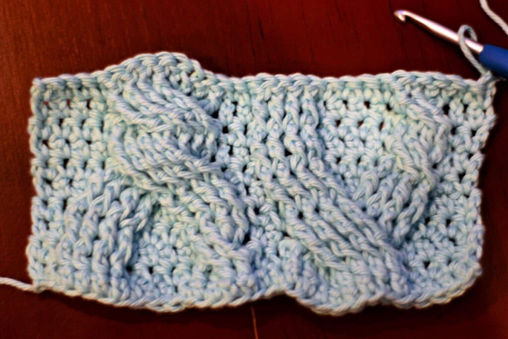 Creating crochet cables with a blue crochet hook.