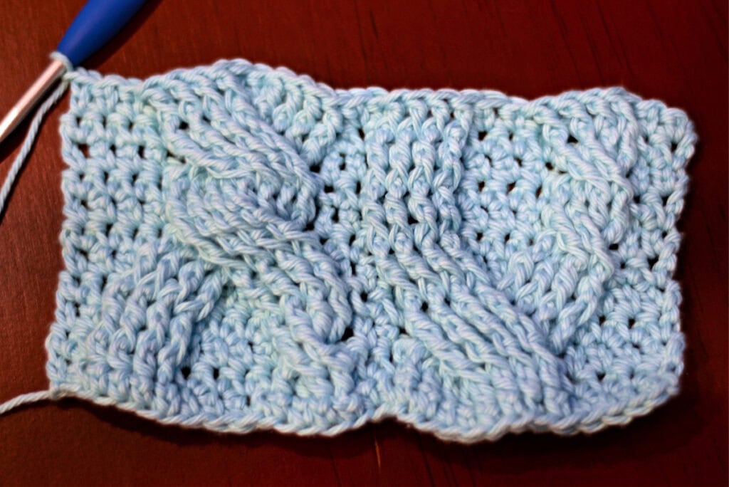 Creating crochet cables with a blue crochet hook.