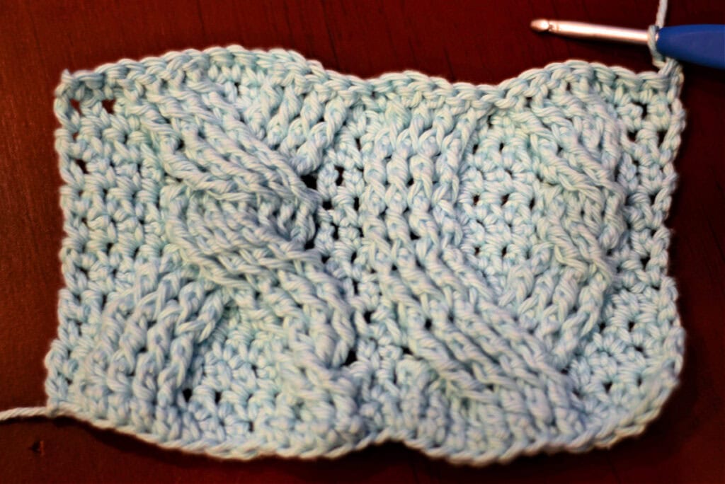 Creating crochet cables with a blue crochet hook.