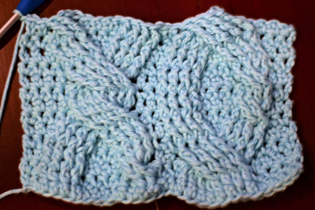Creating crochet cables with a blue crochet hook.