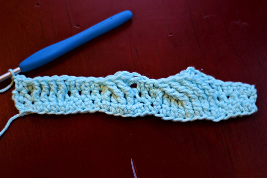 Creating crochet cables with a blue crochet hook.