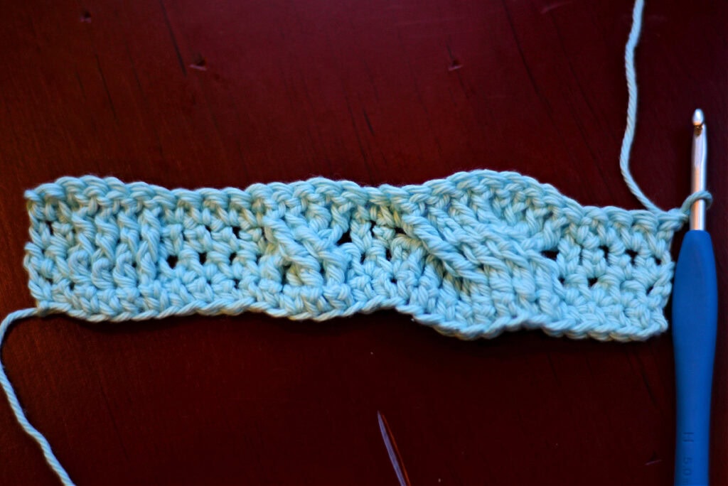 Creating crochet cables with a blue crochet hook.
