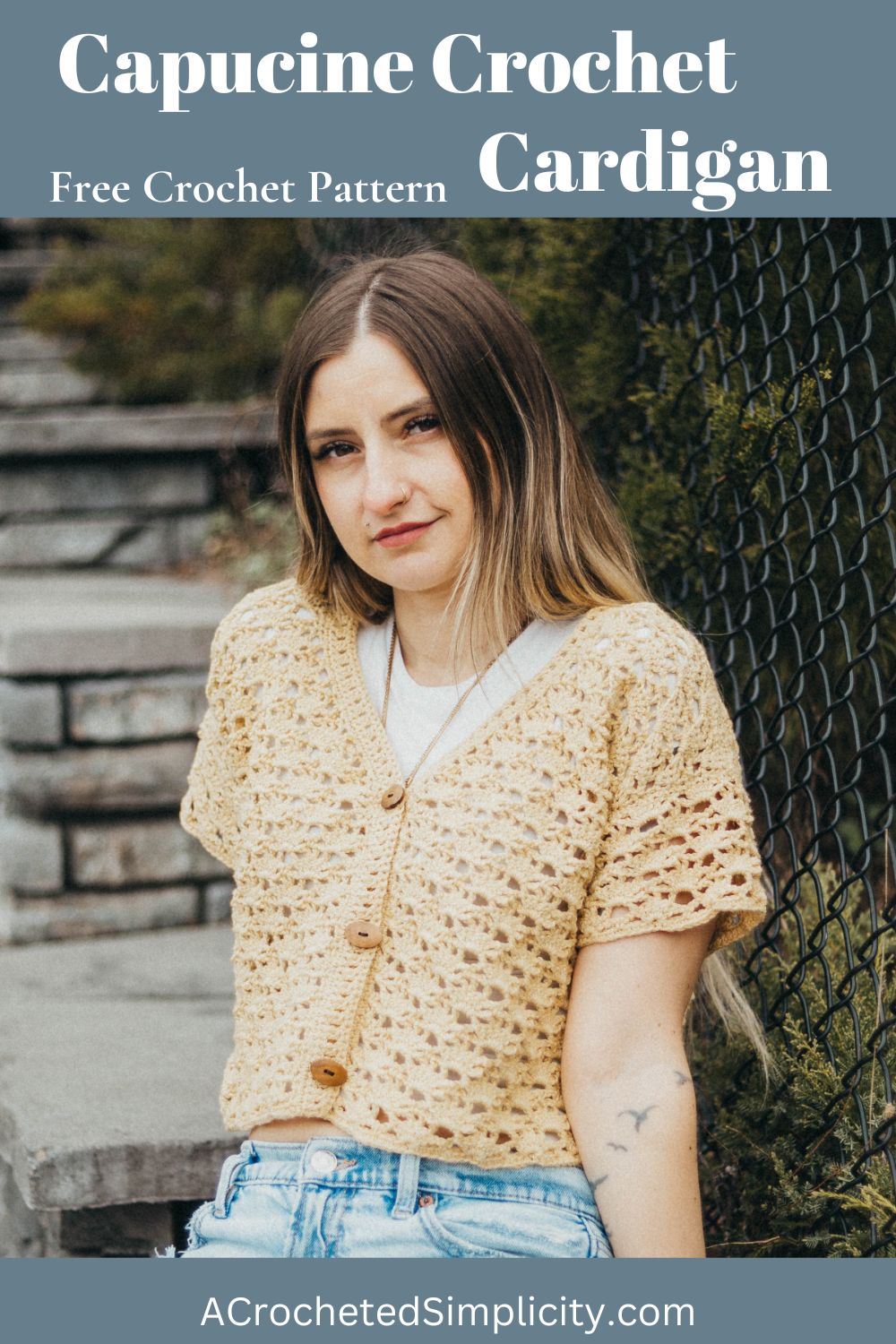 Girl wearing a beige colored cropped crochet cardigan and blue jeans sitting against a stone wall.