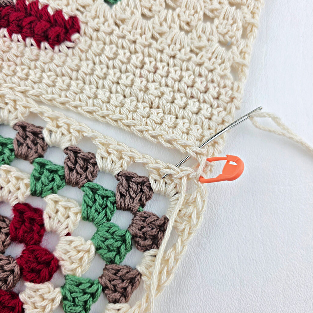 A granny triangle being attached to a white crochet piece.