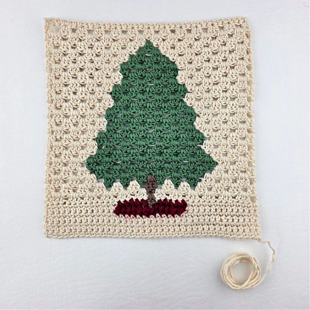 A fir tree made from green and brown yarn against a white background.