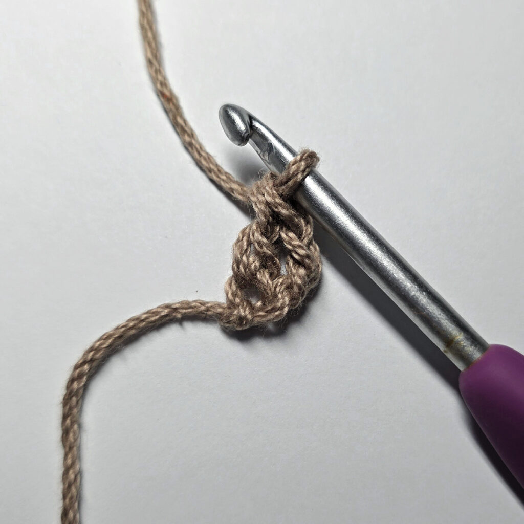 Making a crochet acorn with brown yarn.