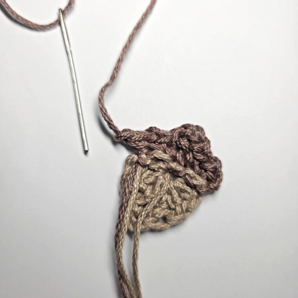 Making a crochet acorn with brown yarn.