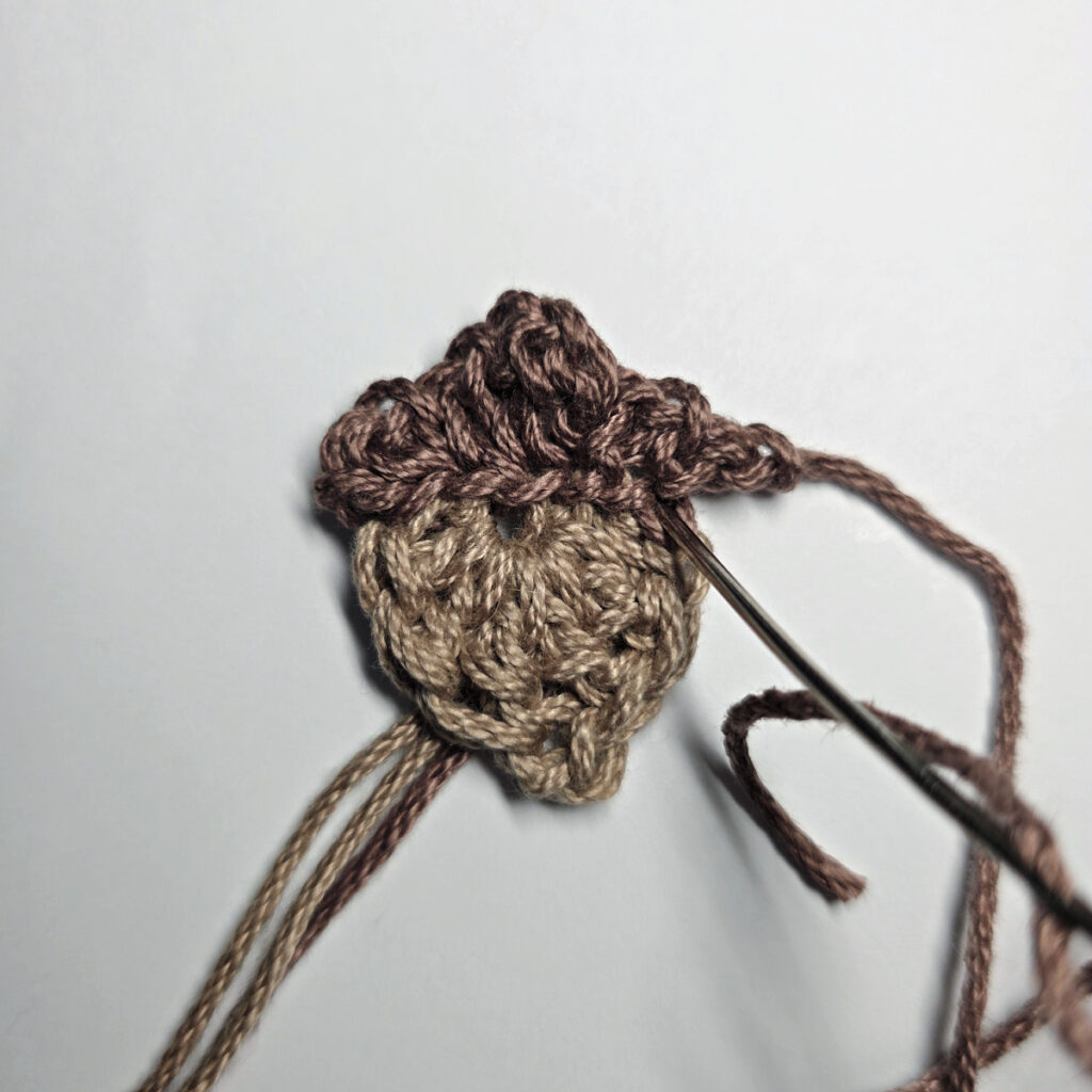 Making a crochet acorn with brown yarn.