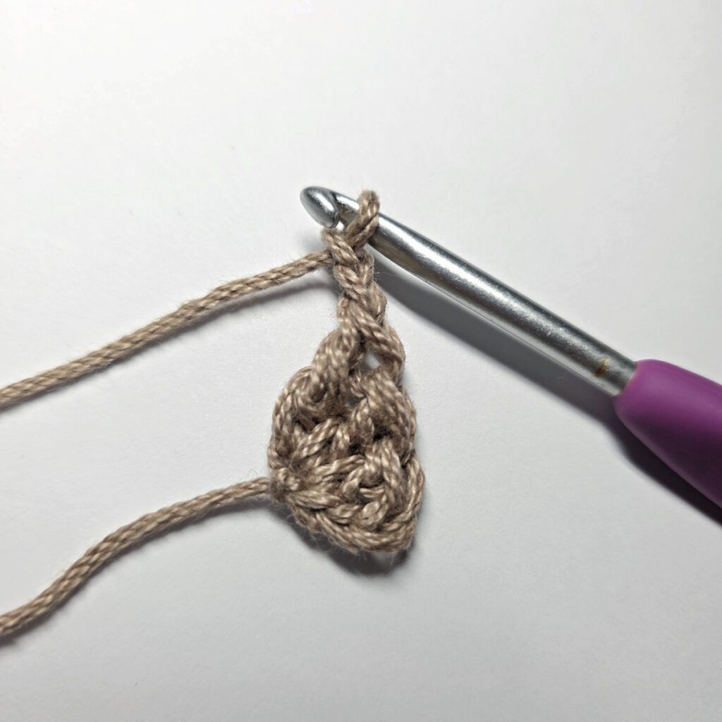Making a crochet acorn with brown yarn.
